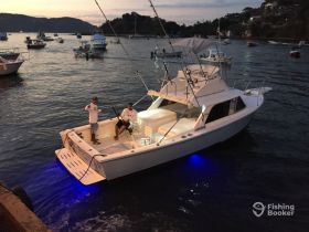 Two fishermen enjoy a tranquil evening on their boat, ready for a fishing adventure as the sun sets over the water.