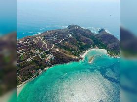 A stunning aerial view of a picturesque coastline with turquoise waters and lush greenery, perfect for showcasing beautiful island destinations.