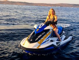 A woman enjoys an exhilarating ride on a jet ski in clear waters, showcasing the thrill of water sports and adventure activities available in Malta.