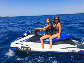 Two friends enjoy a thrilling ride on a jet ski in vibrant blue waters, capturing the essence of summer fun and adventure on the water.