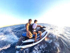 Two friends enjoy an exhilarating ride on a jet ski, capturing the thrill of adventure on the open water.