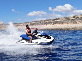 A thrilling moment captured as a rider speeds across the water on a jet ski, showcasing the excitement of water sports in a stunning coastal setting.