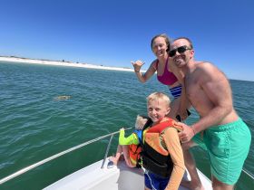 A joyful family enjoys a day on the water, capturing a fun moment while spotting wildlife. Perfect for memorable boating adventures with loved ones.