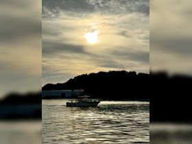 A speedboat glides across the shimmering water at sunset, creating a picturesque scene perfect for evening cruises.