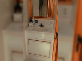 A clean and well-appointed bathroom sink area inside a boat cabin, featuring essential toiletries and a mirror, perfect for onboard comfort.