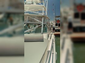 A close-up view of a yacht docked at the marina, showcasing its sleek design and structure, with people visible in the background.