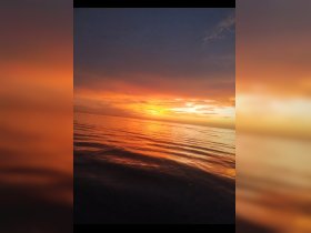 A stunning sunset casts vibrant colors over calm waters, creating a picturesque scene perfect for romantic evenings or tranquil boat rides.