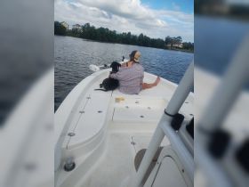 A woman enjoys a peaceful moment on a boat with her dog, surrounded by serene waters and lush greenery — perfect for a relaxing day on the water.
