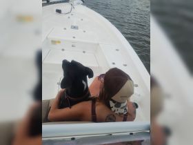 A woman enjoys a relaxing moment on a boat with her dog, showcasing the joy of companionship on the water.