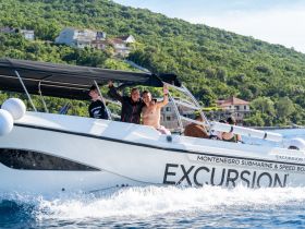 A lively group enjoys a boat excursion in Montenegro, showcasing smiles and excitement as they wave from their speedboat.