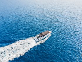 Aerial view of a boat cruising through vibrant blue waters, showcasing an exciting on-water experience with guests enjoying the ride.