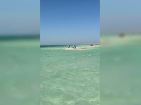A lively group enjoys a sandbar stop in crystal-clear waters, perfect for swimming and relaxation under the sun.