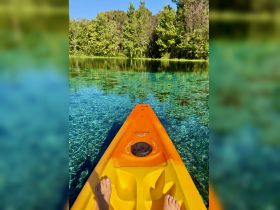 A serene view from a kayak showcasing crystal-clear waters surrounded by lush greenery, perfect for nature lovers and adventure seekers.