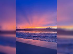 A breathtaking sunset over the coastline, with a silhouette of a boat in the distance — a perfect scene for romantic evenings or tranquil getaways.