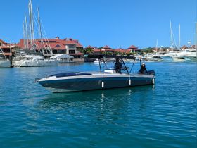 A sleek boat navigates through a vibrant marina, with people onboard enjoying the sunny day — perfect for water adventures and exploration.