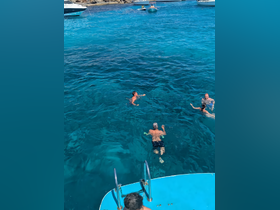 A lively group enjoys swimming in crystal-clear waters, showcasing the perfect setting for a fun day on the boat.