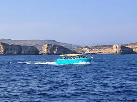 A vibrant blue speedboat navigates through the clear waters, showcasing the stunning coastal cliffs in the background — perfect for exploring scenic destinations.