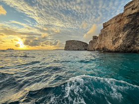 A stunning sunset over the coastline, with waves gently lapping at the shore — a perfect backdrop for a memorable boating experience.