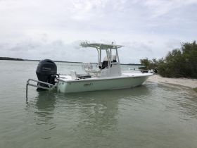 A sleek center console boat anchored in shallow waters, showcasing its design and functionality against a serene natural backdrop.
