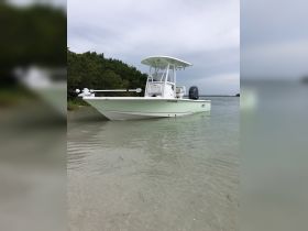 A pristine center console boat docked in shallow waters, surrounded by lush greenery — perfect for fishing or leisurely outings.