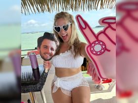 A lively moment captured on a boat as a woman playfully poses with a fun prop and drinks, embodying the spirit of celebration and enjoyment on the water.