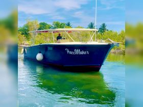 The 'PeaceMaker' boat is docked in serene waters, showcasing its sleek design against a backdrop of lush greenery, perfect for tranquil getaways.