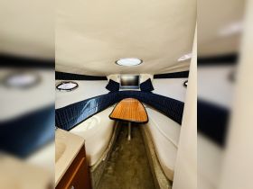 Interior view of a cozy boat cabin featuring comfortable seating and a mounted TV, perfect for relaxing on the water.