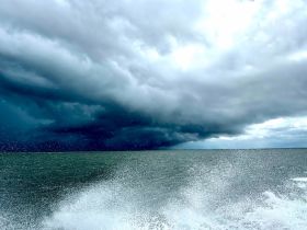 A dramatic view of an approaching storm over the ocean, showcasing turbulent clouds and splashing waves — a captivating moment on the water.