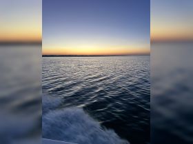 A serene sunset view over calm waters, captured from a boat, showcasing the tranquil beauty of evening cruises.