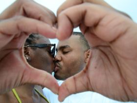 A romantic moment captured as a couple shares a kiss framed by hands forming a heart — perfect for celebrating love on a boating adventure.