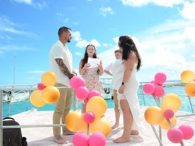 A joyful wedding ceremony takes place on a boat, surrounded by family and colorful decorations, capturing a beautiful moment on the water.