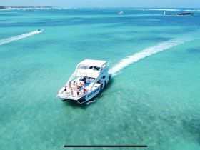 A lively group enjoys a day on the water aboard a charter boat, cruising through stunning turquoise waters — perfect for group adventures and fun on the sea.