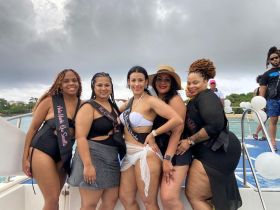 A lively group of friends celebrates a bachelorette party aboard a boat, showcasing fun and camaraderie against a scenic backdrop.