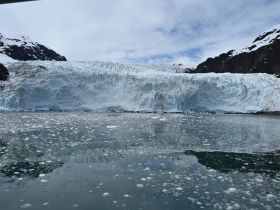 A stunning view of a glacier reflecting in the calm waters, surrounded by majestic mountains — a breathtaking natural wonder perfect for eco tours.