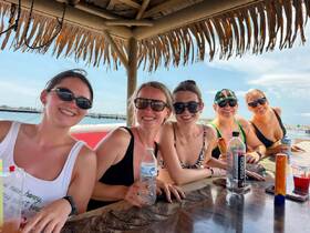 A group of friends enjoys drinks and laughter at a tropical bar, perfect for celebrating special moments together on the water.