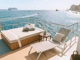 A cozy lounge area on a boat featuring comfortable seating and a beautiful view of the ocean, perfect for relaxation while enjoying the sea breeze.