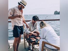 A group of friends enjoys a game of backgammon on the deck of a boat, surrounded by the beautiful ocean — perfect for a fun day at sea.