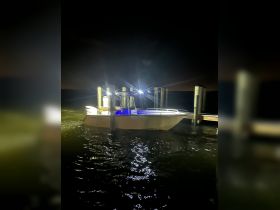 A well-lit boat docked at night, showcasing its sleek design and illuminated features against the dark waters.