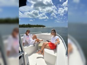 Two friends relax on the deck of a boat under a sunny sky, enjoying a perfect day on the water — ideal for social outings and adventures.