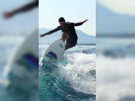 A surfer catches air while riding a wave, showcasing the thrill of water sports in a stunning natural setting.