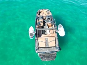 Aerial view of a sleek Centurion boat cruising through clear turquoise waters, showcasing its stylish design and spacious seating.