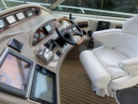 A detailed view of the helm and seating area inside a luxury boat, showcasing modern navigation equipment and comfortable seating for an enjoyable boating experience.
