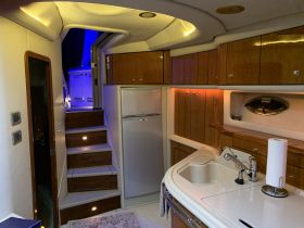 Interior view of a well-appointed boat cabin featuring a kitchen area, showcasing elegant wood finishes and modern amenities — perfect for comfortable cruising.