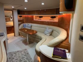 A cozy and elegantly designed interior of a boat featuring a spacious lounge area with comfortable seating and ambient lighting, perfect for relaxation while at sea.