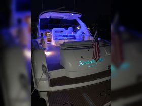 A beautifully lit interior of the 'Kimberly Ann' yacht, showcasing comfortable seating and a stylish helm, perfect for evening cruises.
