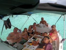 A joyful group enjoys a meal aboard a boat, showcasing a fun day on the water with family and friends, perfect for memorable celebrations.