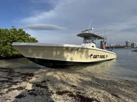 A fishing boat named 'GET REEL' is anchored at the shoreline with a man preparing for a day on the water, showcasing the excitement of fishing adventures.