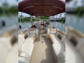 Interior view of a spacious pontoon boat featuring comfortable seating and a helm, perfect for relaxing on the water.