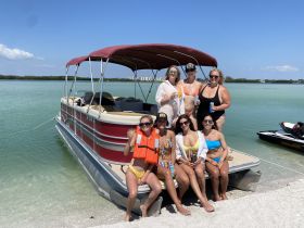 A lively group of friends enjoys a fun day on a pontoon boat, celebrating with drinks by the water — perfect for summer outings and memorable gatherings.