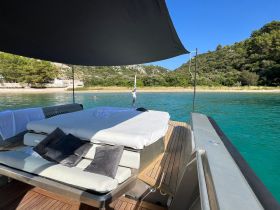 A stylish lounge area on a boat, featuring comfortable seating and shade, perfect for relaxing while enjoying the beautiful turquoise waters.
